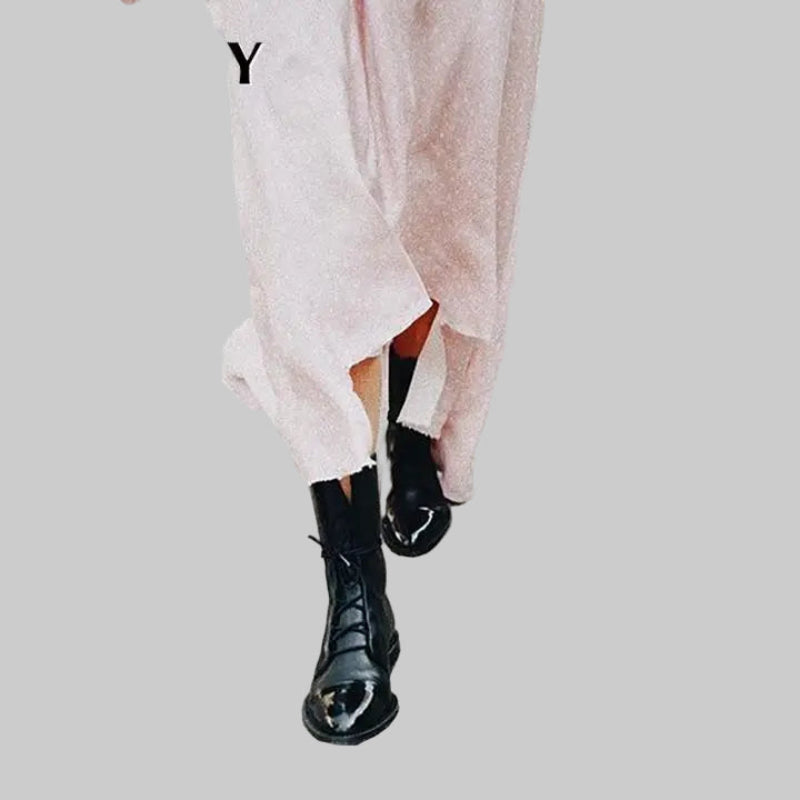 Person wearing black boots and a light pink dress-front view