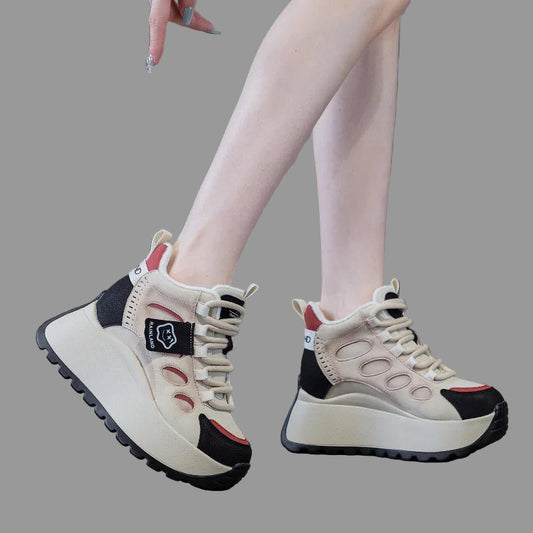 White genuine leather sneakers with black and red accents worn by a person on a gray floor.